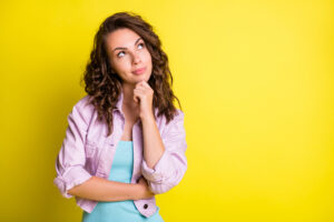 Woman looking curious against a yellow background.
