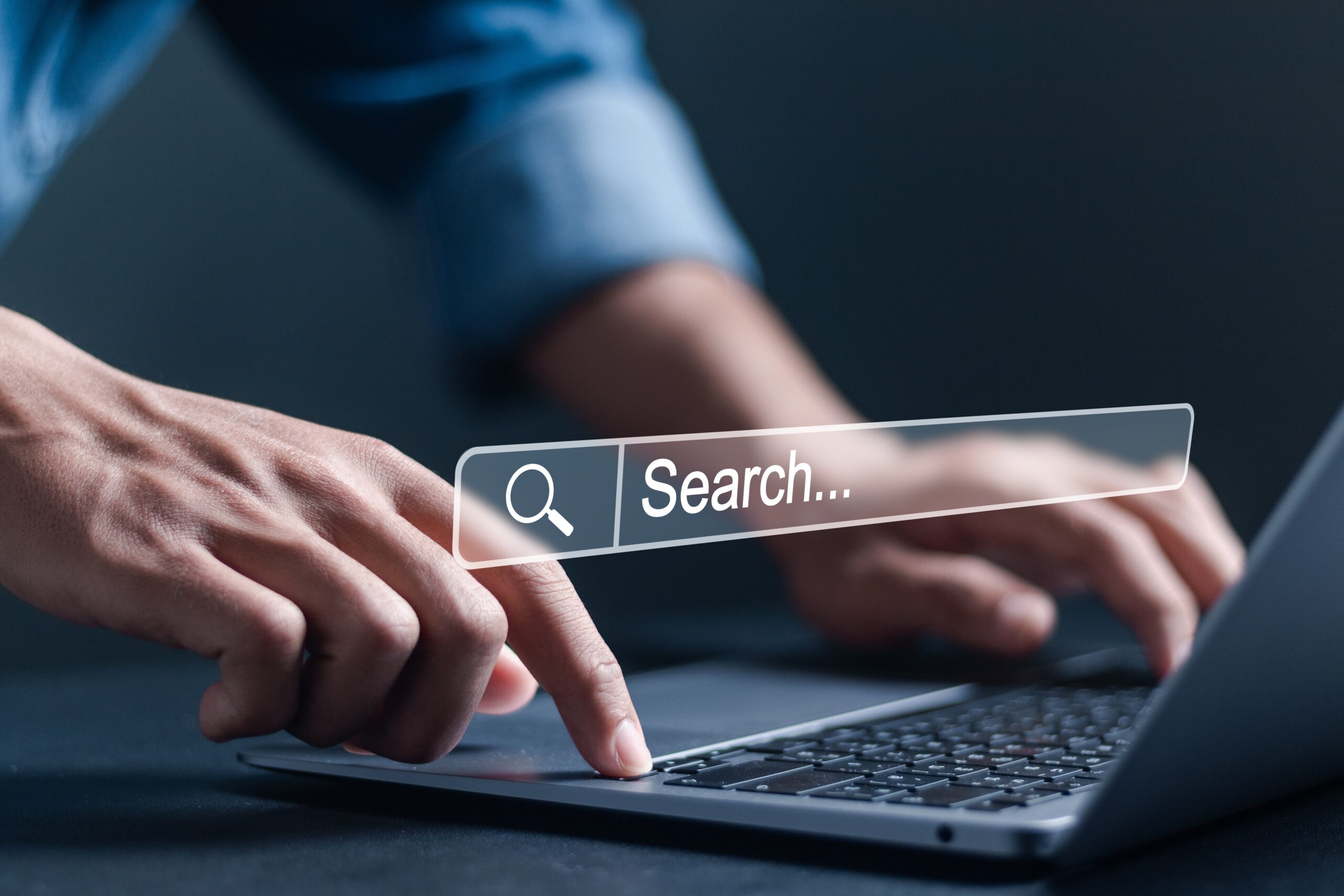 Search bar superimposed over a close-up view of hands on a laptop keyboard