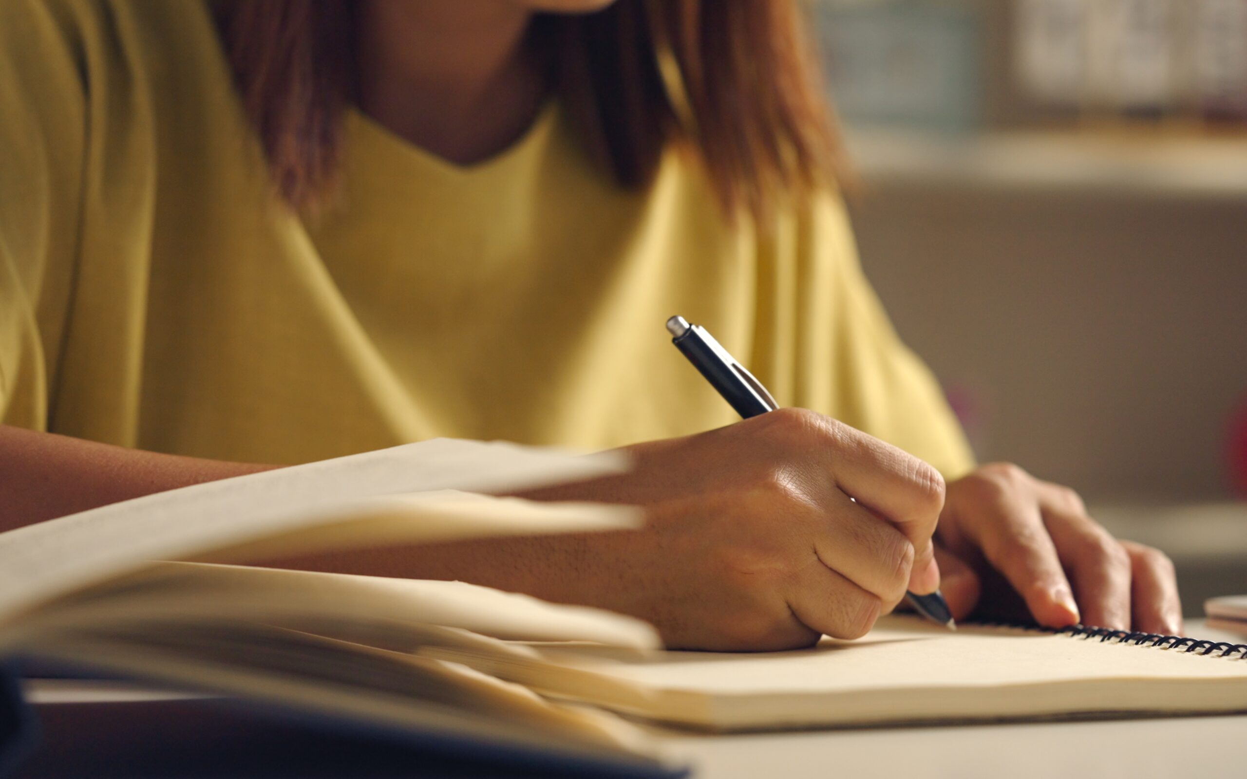 Close-up of a copywriter holding a pen, writing in a notebook